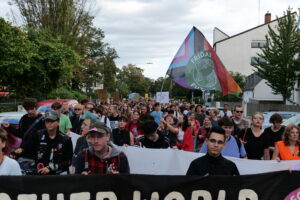 Der Demozug befindet sich in der Wöhrdstraße. In der Mitte der Demo hält eine Person eine große Fridays for Future-Pride-Flag.